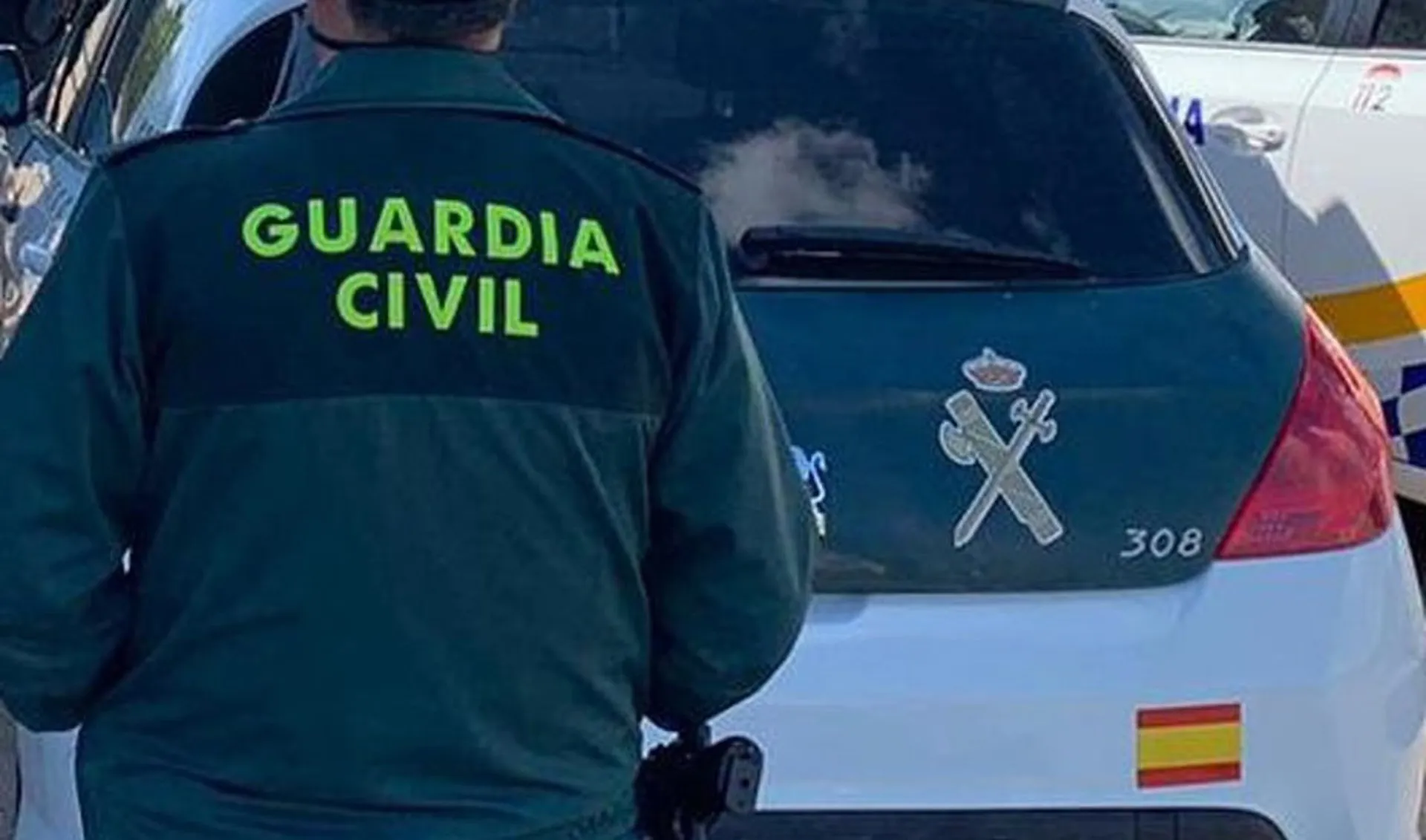 Un agente de la Guardia Civil junto a un vehículo oficial.