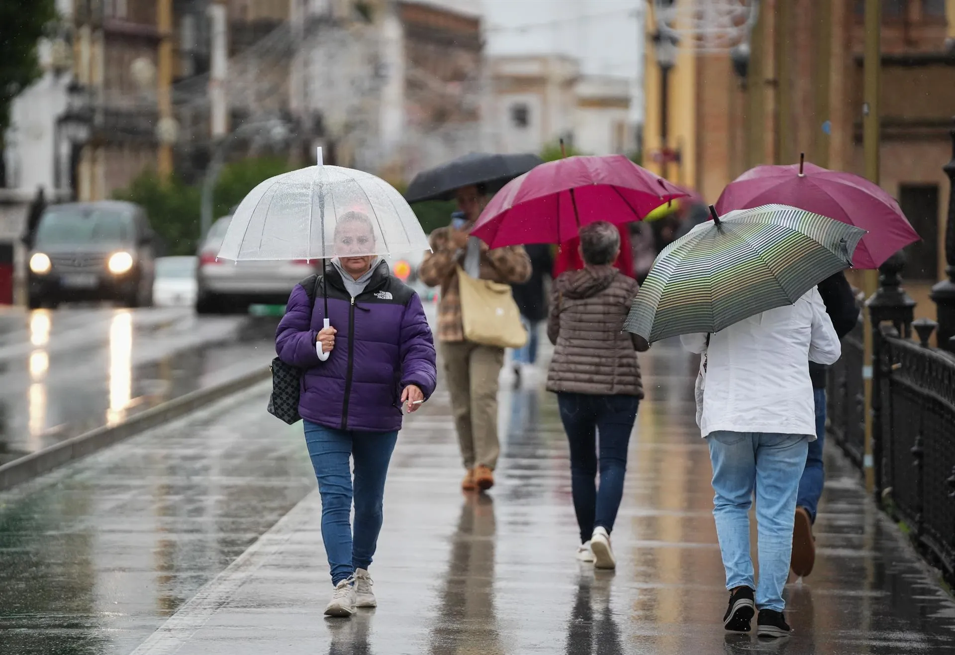 Imagen de archivo de viandantes protegiéndose de la lluvia en Sevilla.