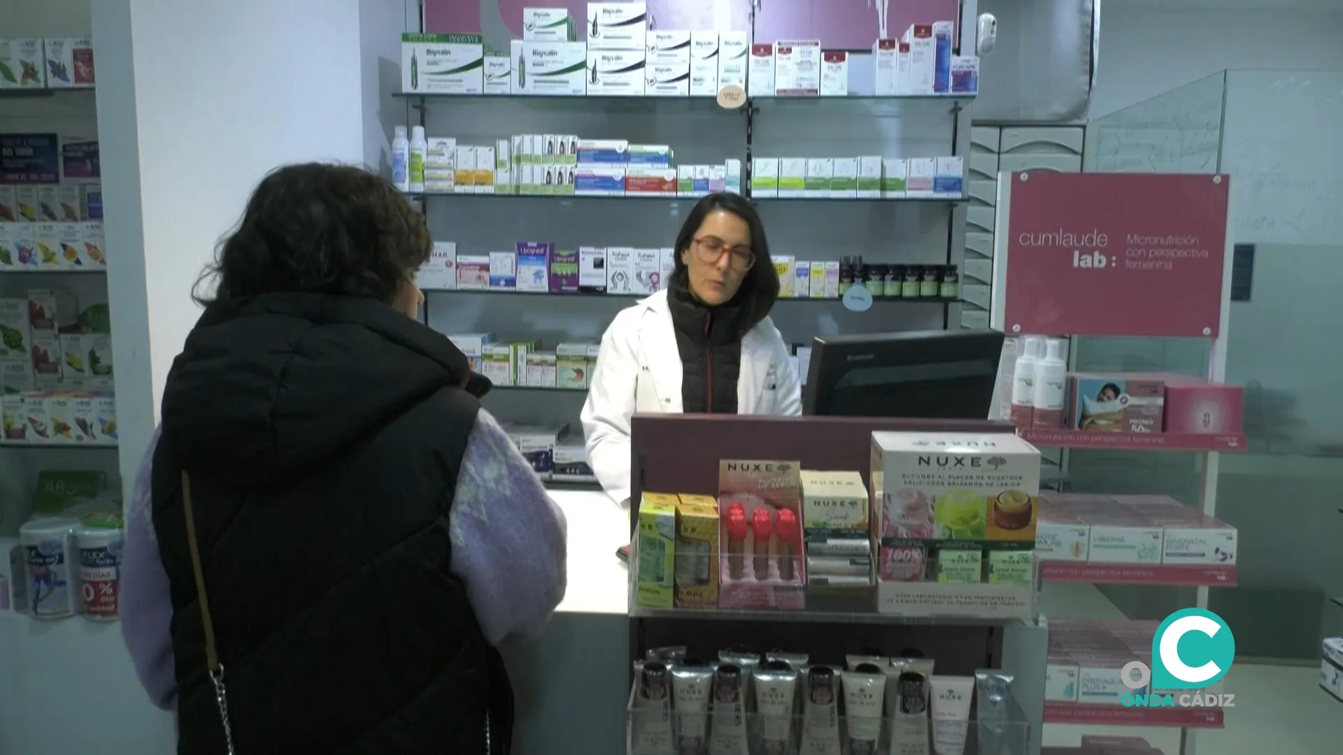 Una profesional atiende a una paciente en una farmacia de Cádiz. 