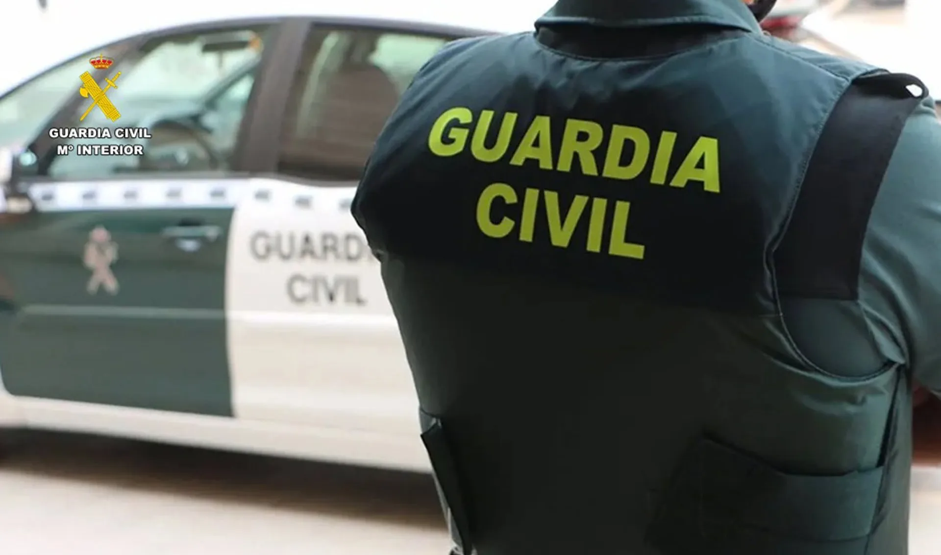 Un agente de la Guardia Civil junto a un vehículo oficial.