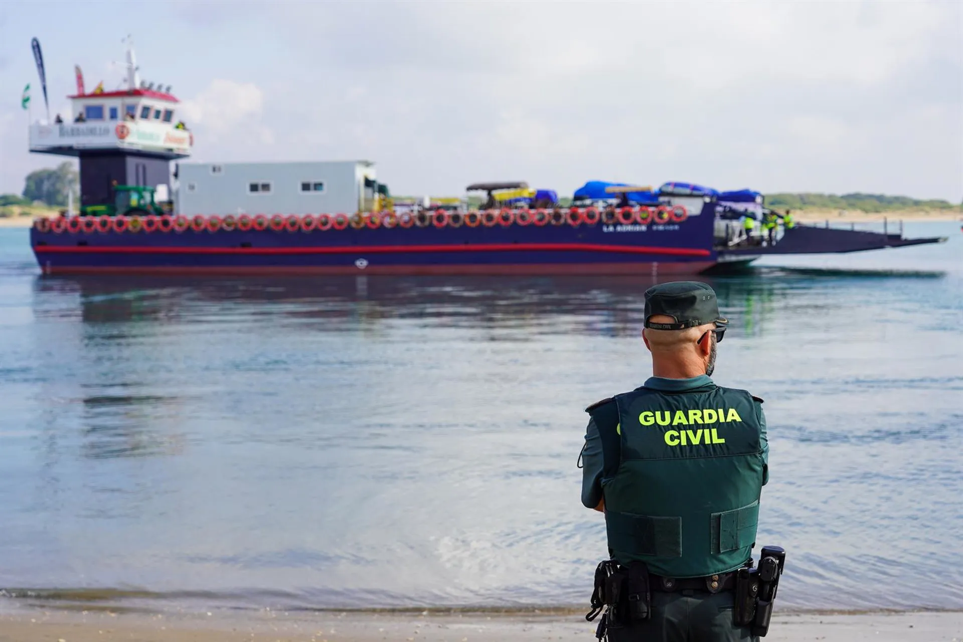 Un agente de la Guardia Civil frente a una barcaza para cruzar el río Guadalquivir camino del Coto de Doñana