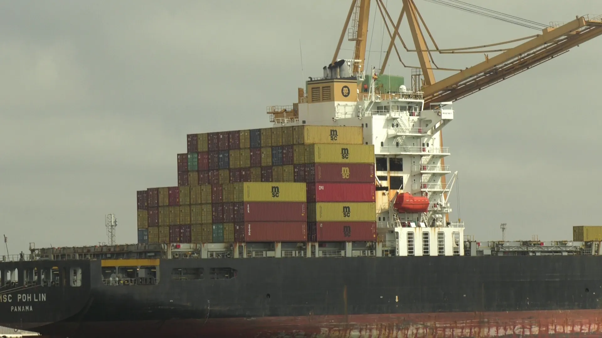 Barco csrgado de contenedores de mercancías en el muelle de la capital gaditana