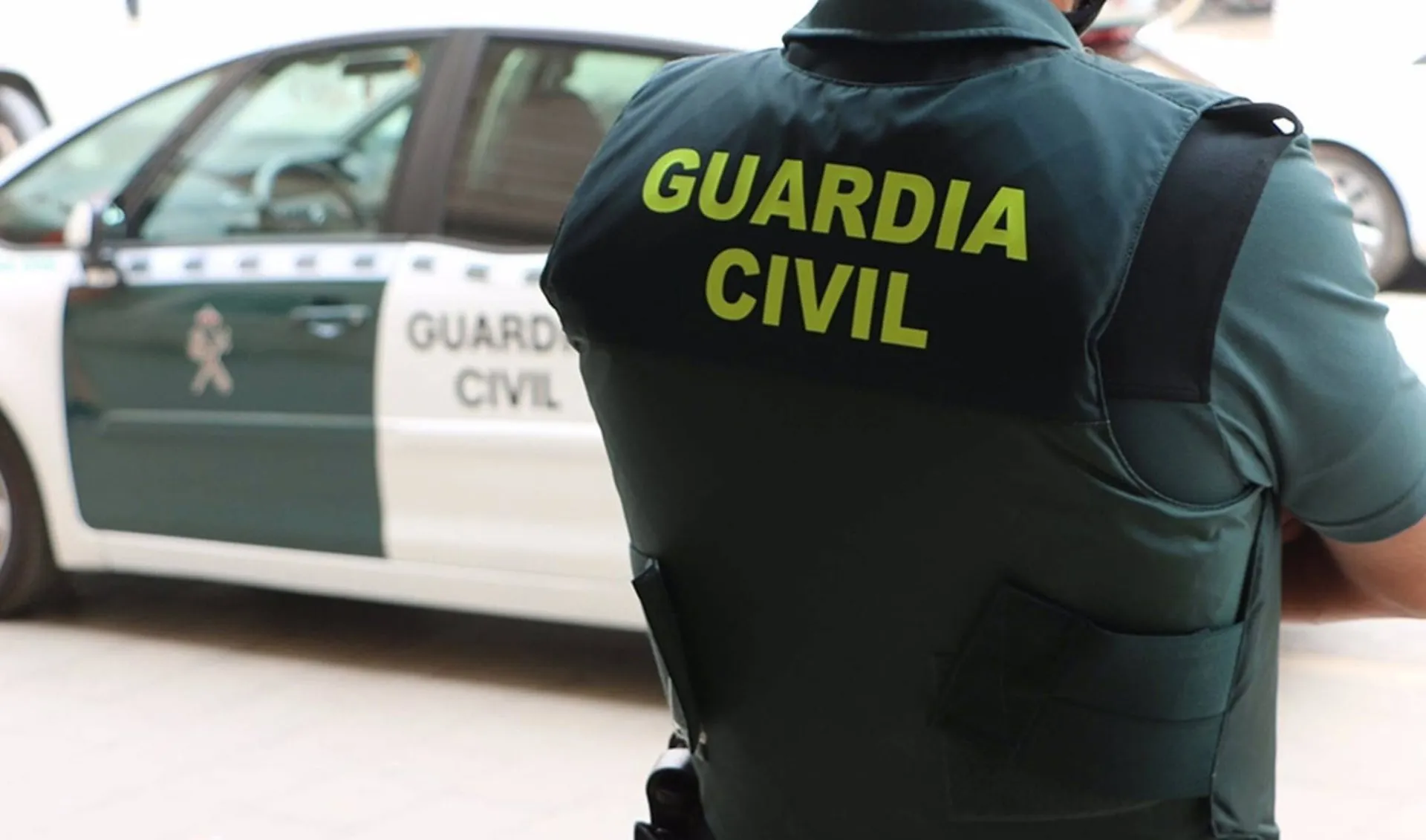 Un agente de la Guardia Civil junto a un vehículo oficial