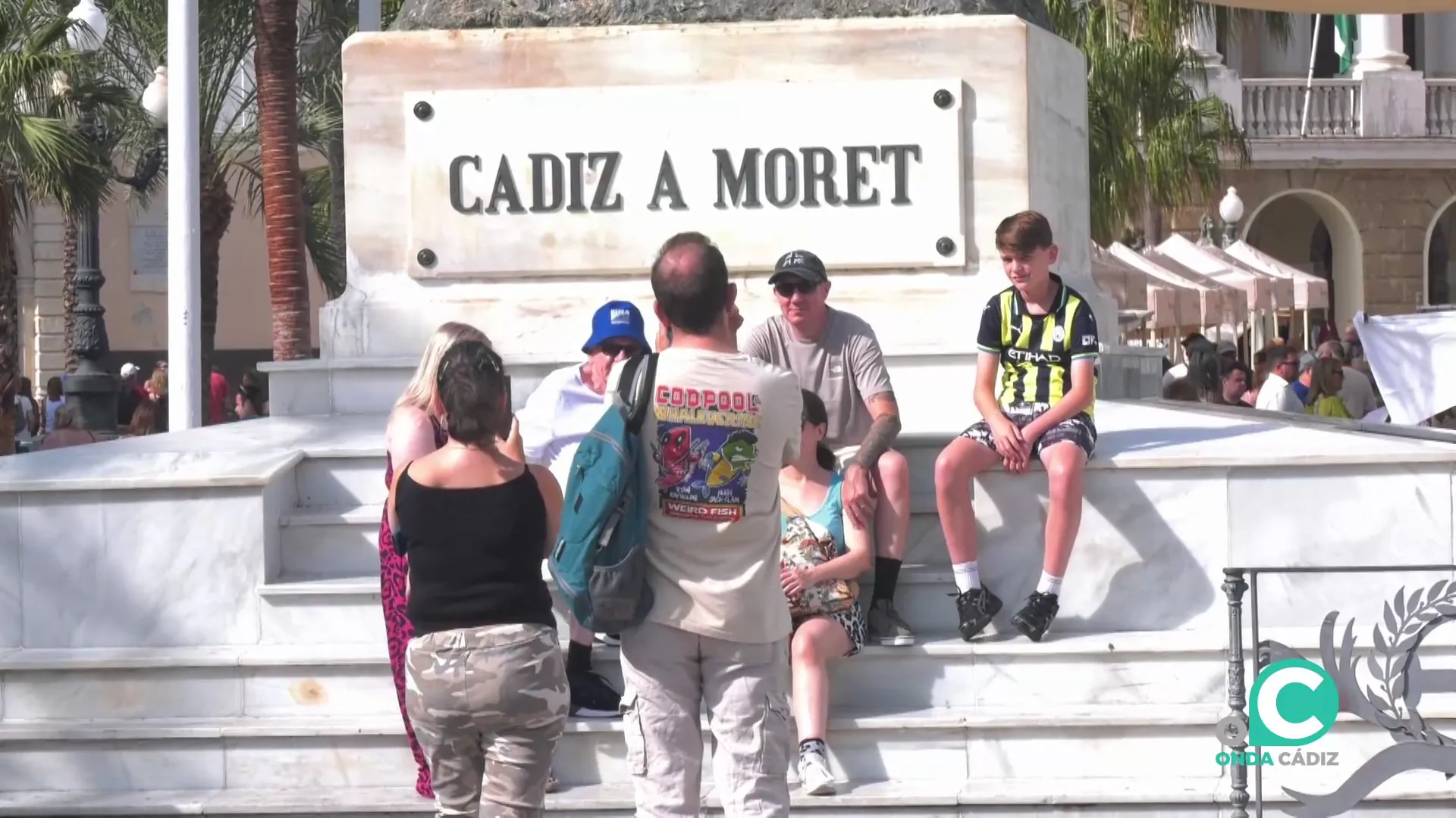 Una familia se fotografía en el monumento a Moret en la plaza San Juan de Dios