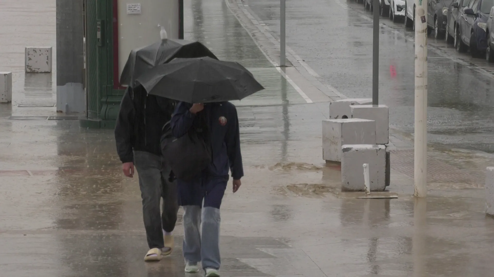 Dos viandantes circulan por el Paseo Marítimo bajo la lluvia